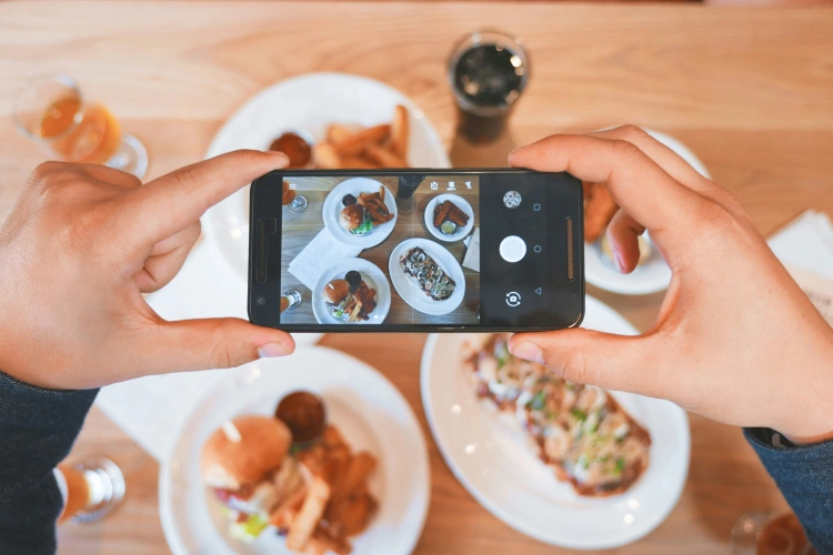 person taking picture of food with phone